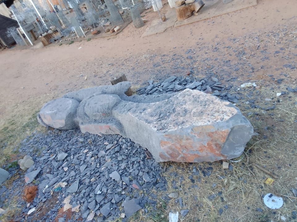 The partly cut stone lying among chippings, with rounded head shapes roughed out along one side