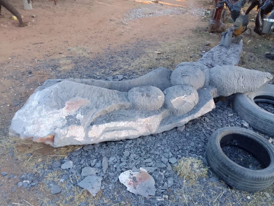 The roughed-out stone beside old tyres, the rounded head shapes clearer