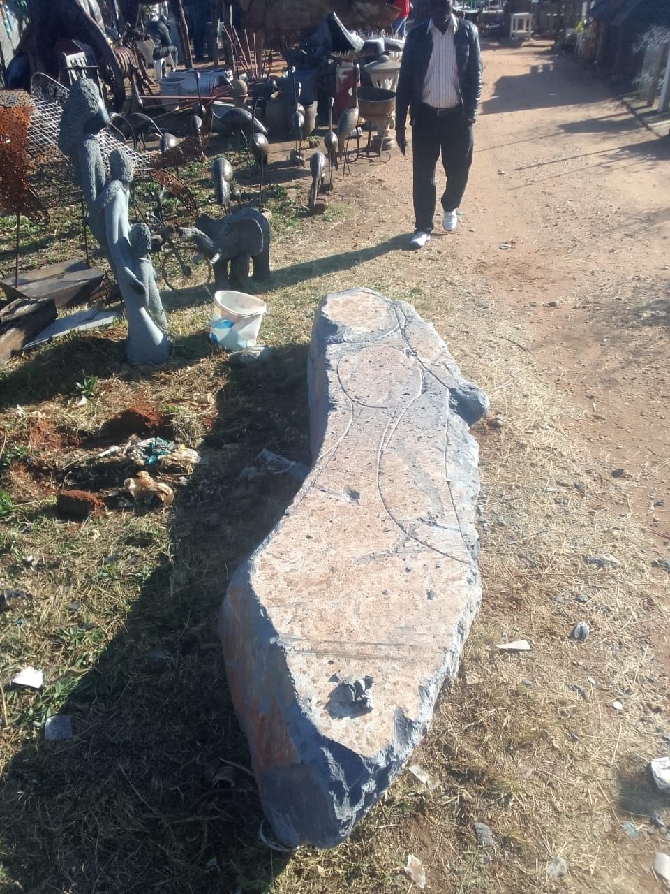 The raw block lying on a path, with the outline of figures marked on its surface