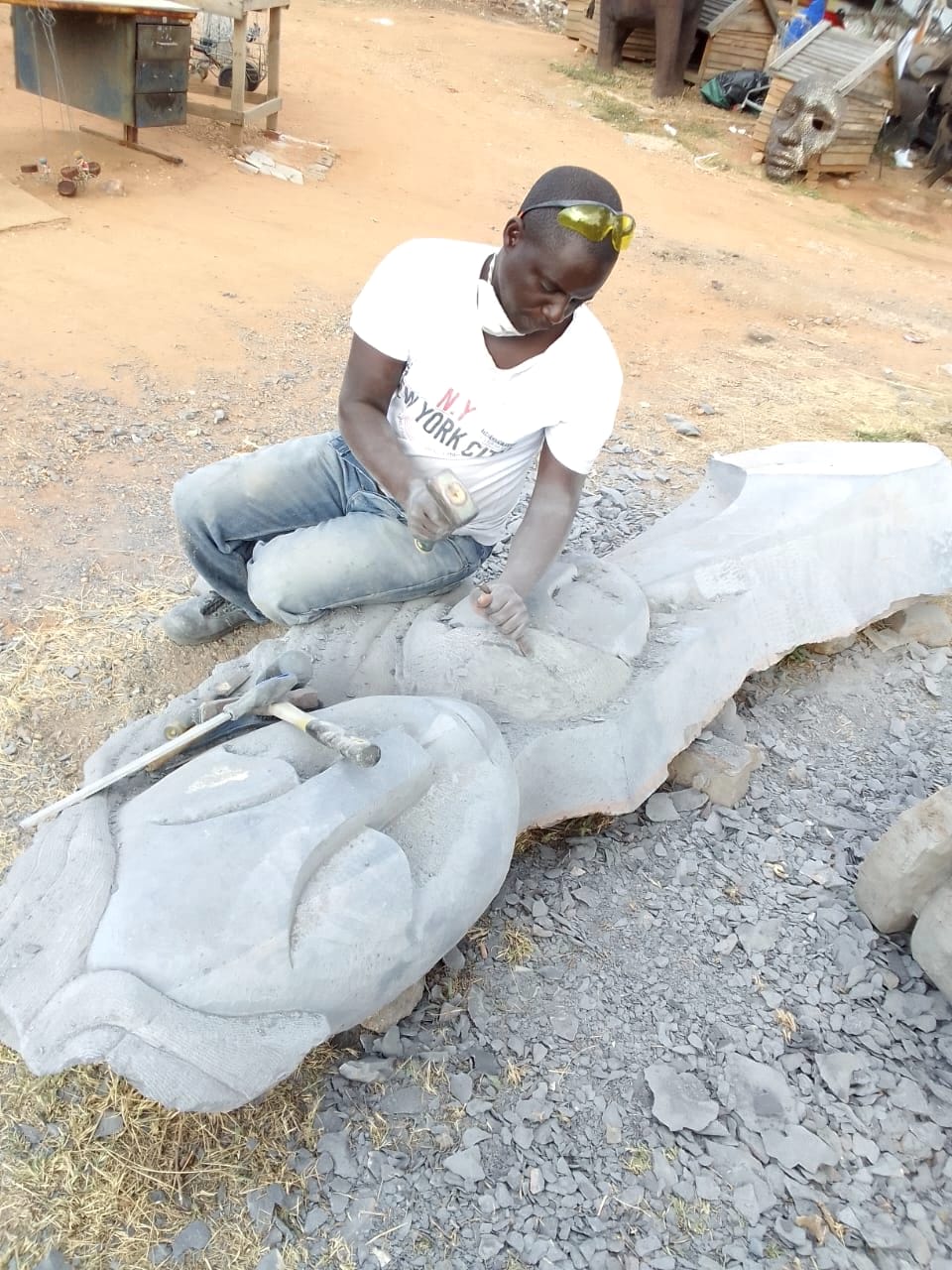 The carver working along the length of the stone, faces beginning to show