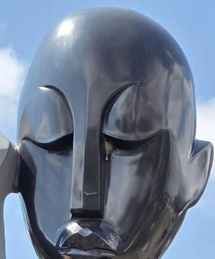The face, eyes lowered, in polished dark stone