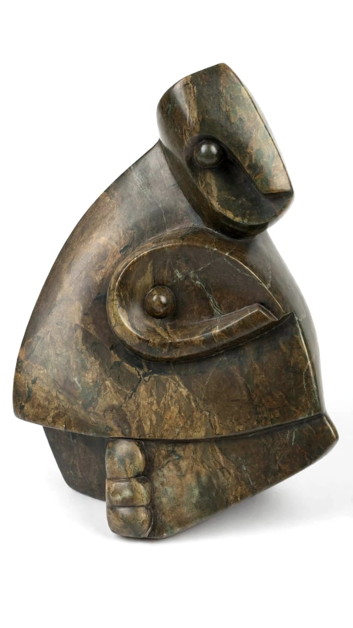 Bronze-green stone figure with ball eyes, leaning forward with a hand at the front, on white