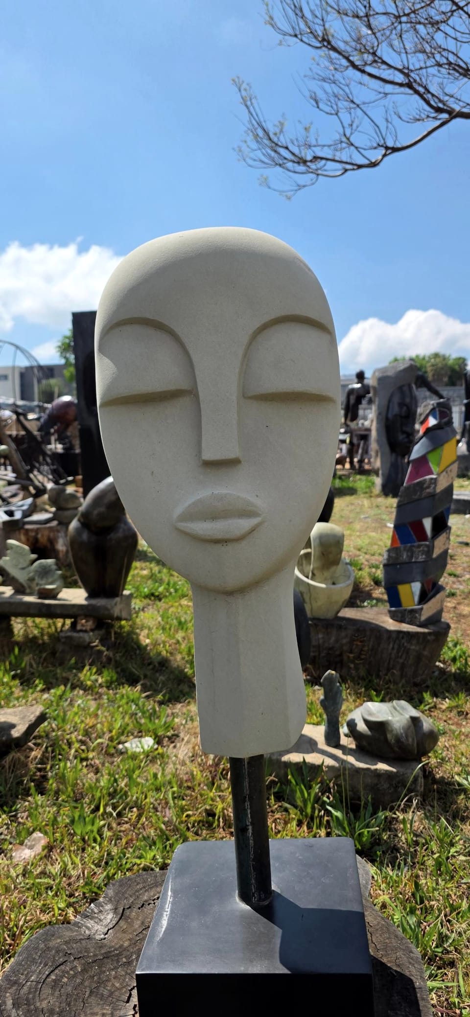 The pale stone head seen slightly closer, against a blue sky