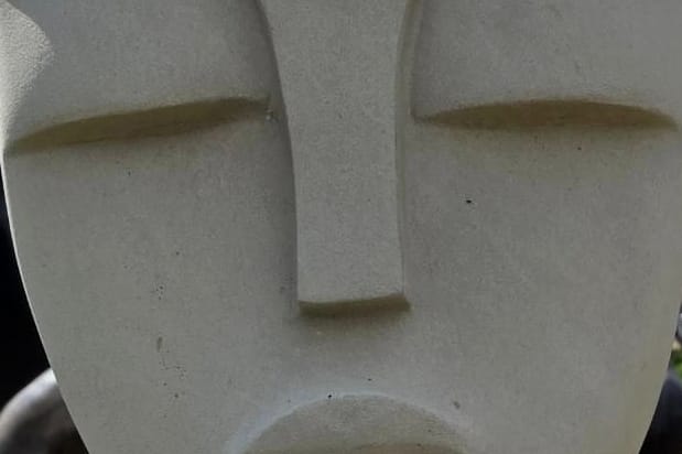 The carved closed eyes and brow line