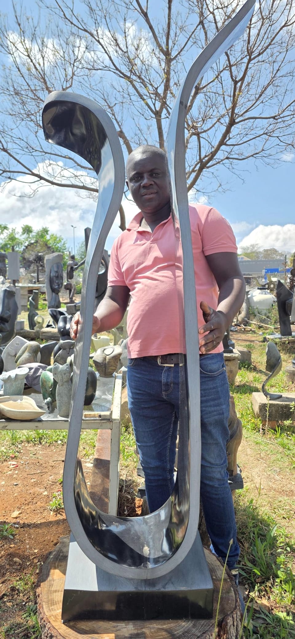 The open ribbon of polished dark stone with Langton standing behind it, his hands on the two curves