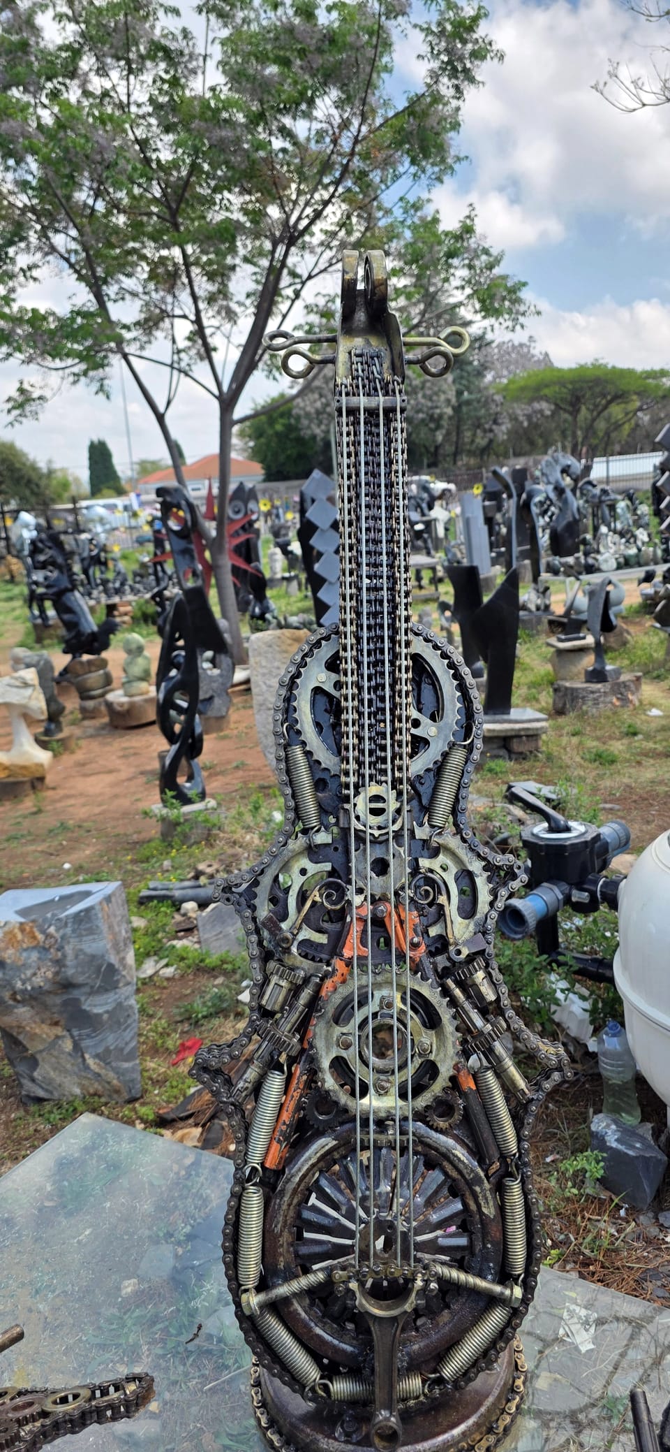 Welded metal cello built from gears, springs and bicycle chain, with wire strings