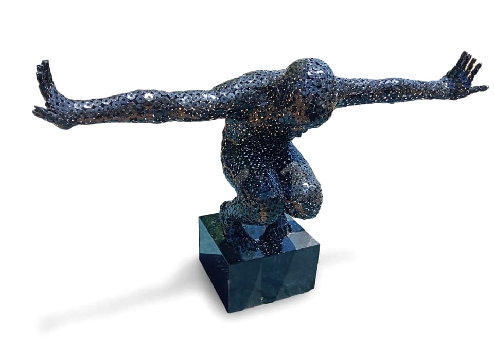 Crouching figure covered in washers, arms outstretched, on a black base