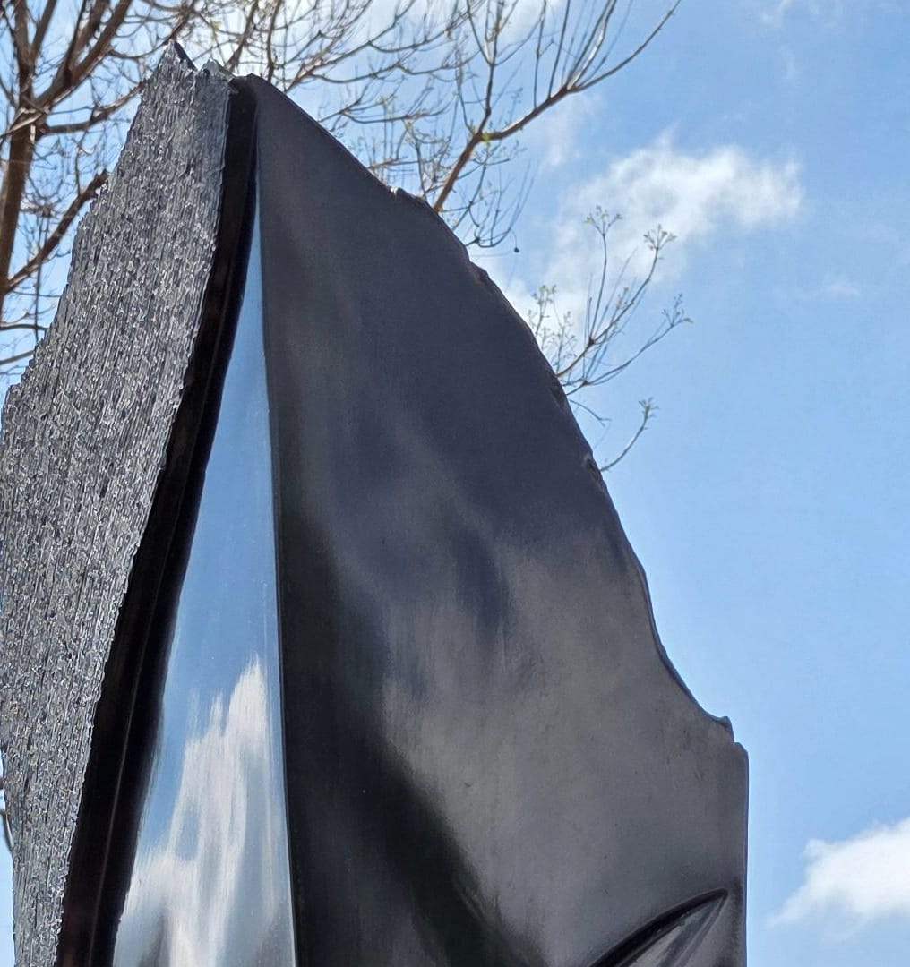 The polished face against the rough-cut edge, reflecting the sky