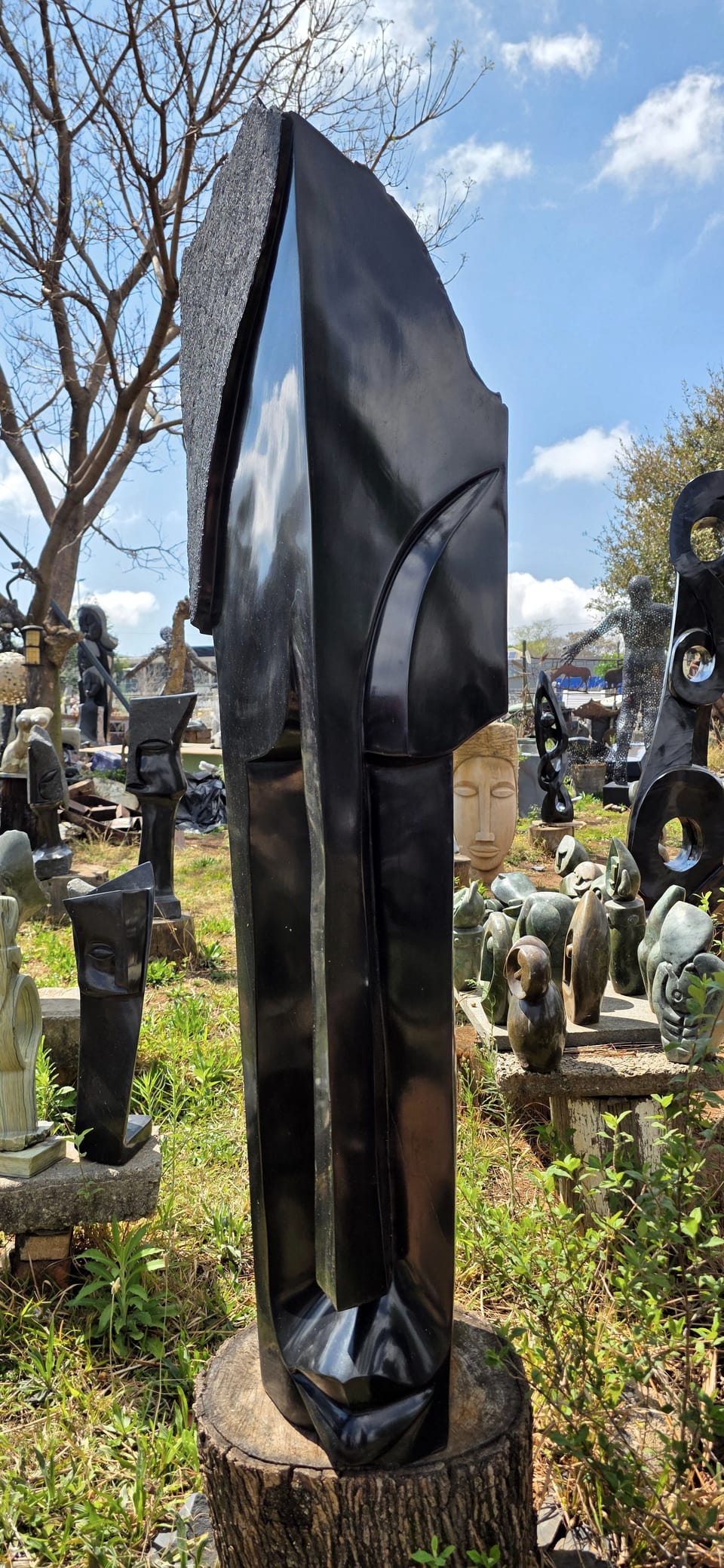 Tall curved blade of polished dark stone with a narrow face carved along its edge