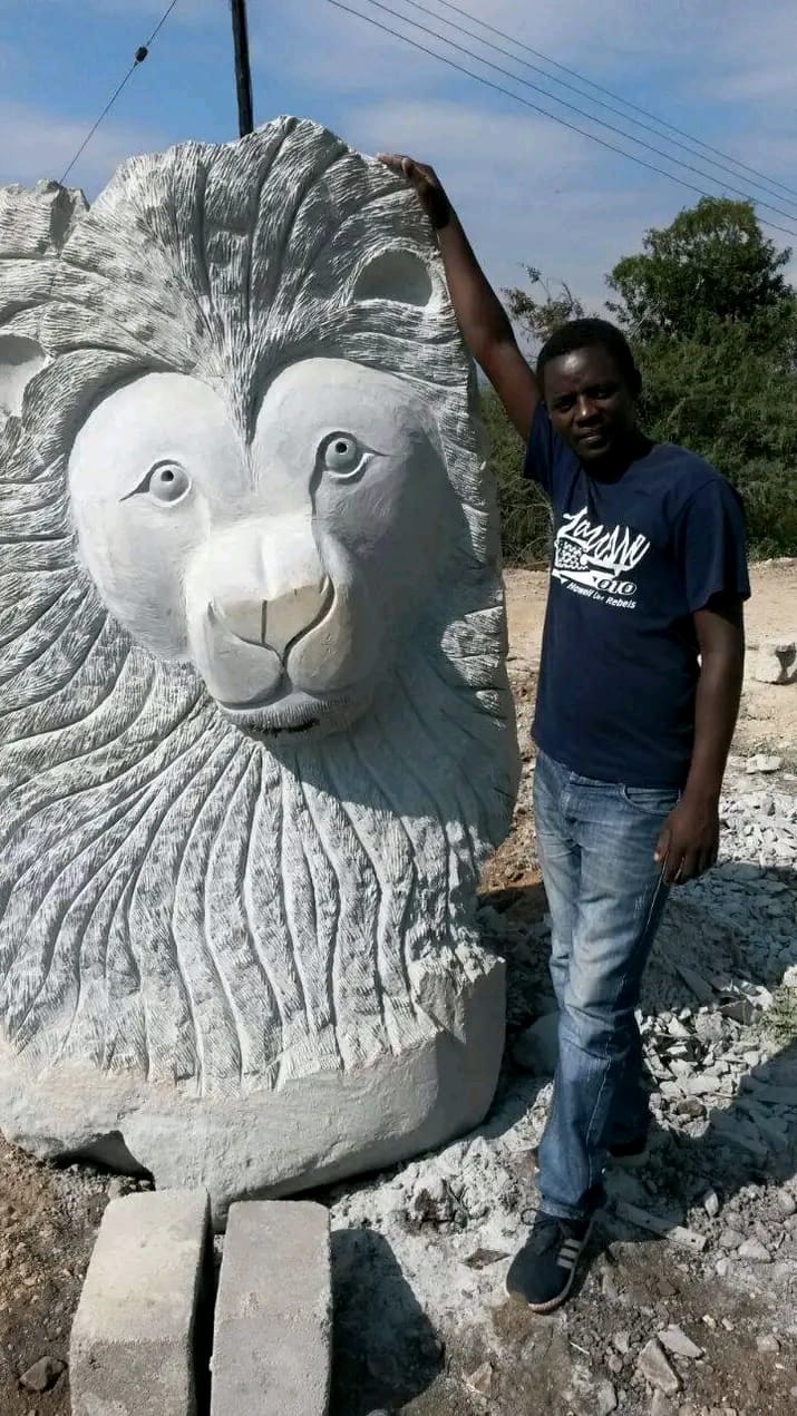 Finished lion head with a detailed mane and calm face, with the artist beside it