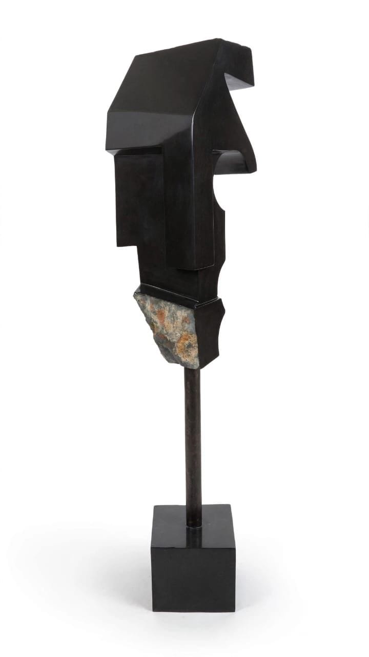 Angular dark stone head with a rough-cut chin, raised on a slim stem and square base, on white